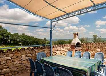 Grande terrasse ombragée avec table, chaises et barbecue