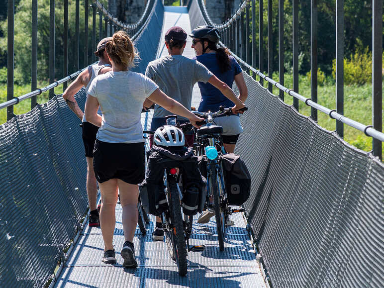 Cyclists cross the Himalayan footbridge over the Rhône